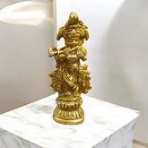 A beautifully crafted brass idol of Lord Krishna, depicting him playing the flute, perfect for worship and home decoration.