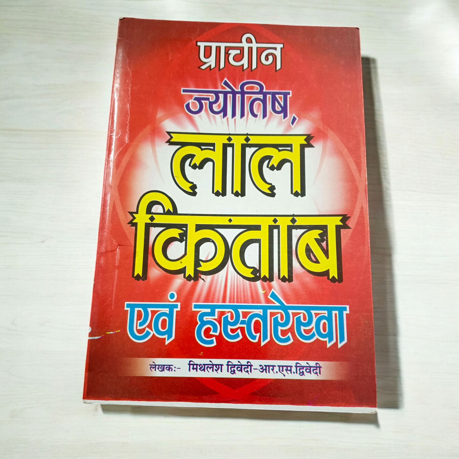 Description of the image: The cover of Lal Kitab Aur Hastrekha Prachin Jyotish | Hindi Book, featuring astrological and palmistry symbols intertwined with ancient mystical designs.