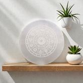 Engraved selenite crystal charging plate with zodiac signs, used for cleansing and recharging crystals, meditation, pooja, and spiritual home décor