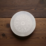 Engraved selenite crystal charging plate with zodiac signs, used for cleansing and recharging crystals, meditation, pooja, and spiritual home décor