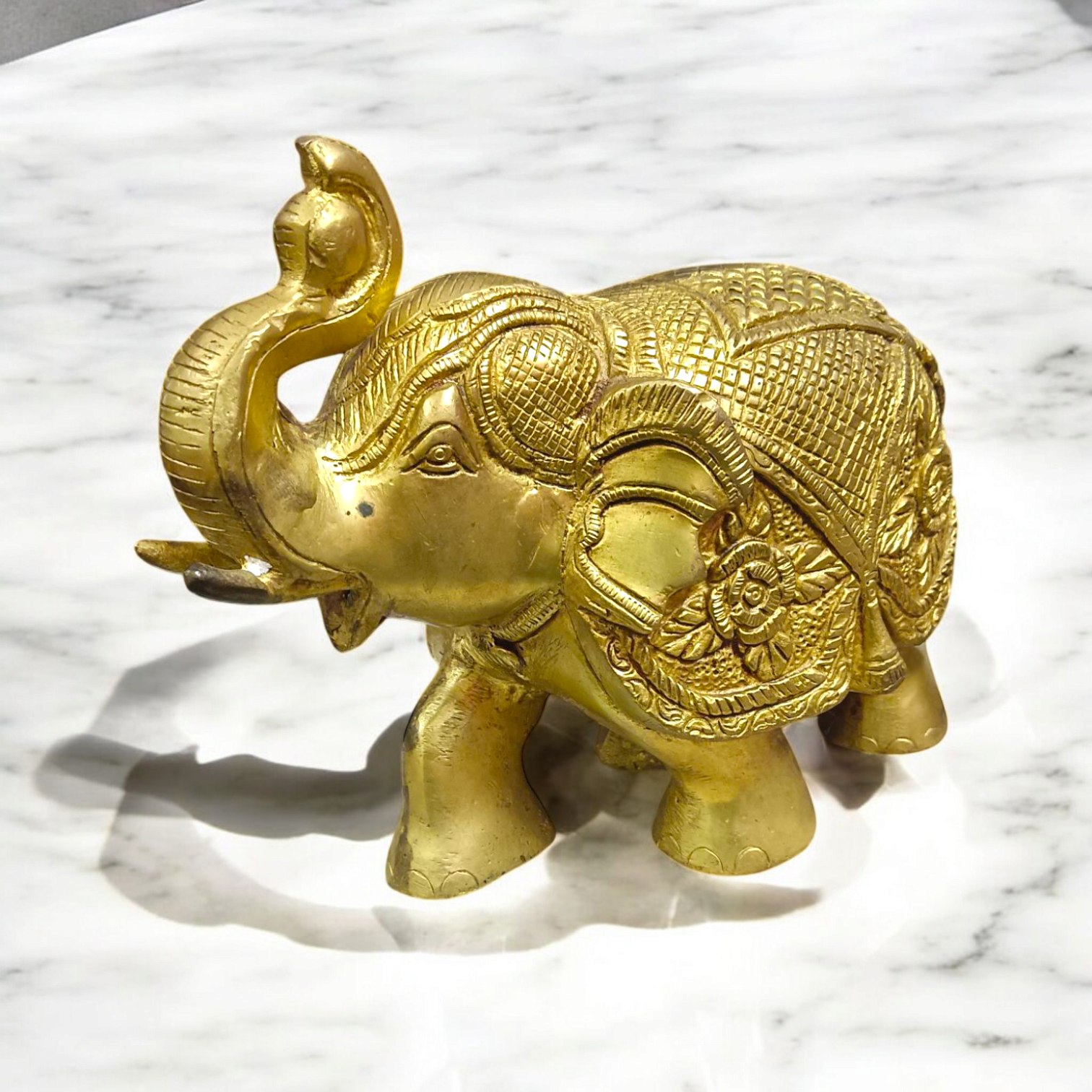 A beautifully crafted large brass elephant statue with an intricate design, symbolizing strength, prosperity, and good fortune, placed on an office table.

