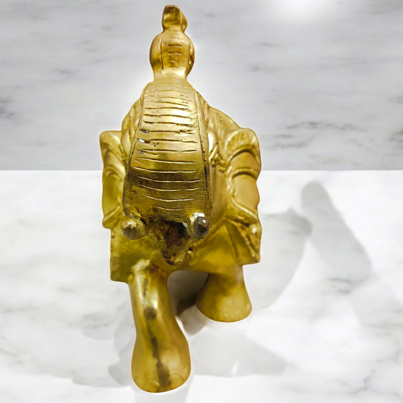 A beautifully crafted large brass elephant statue with an intricate design, symbolizing strength, prosperity, and good fortune, placed on an office table.

