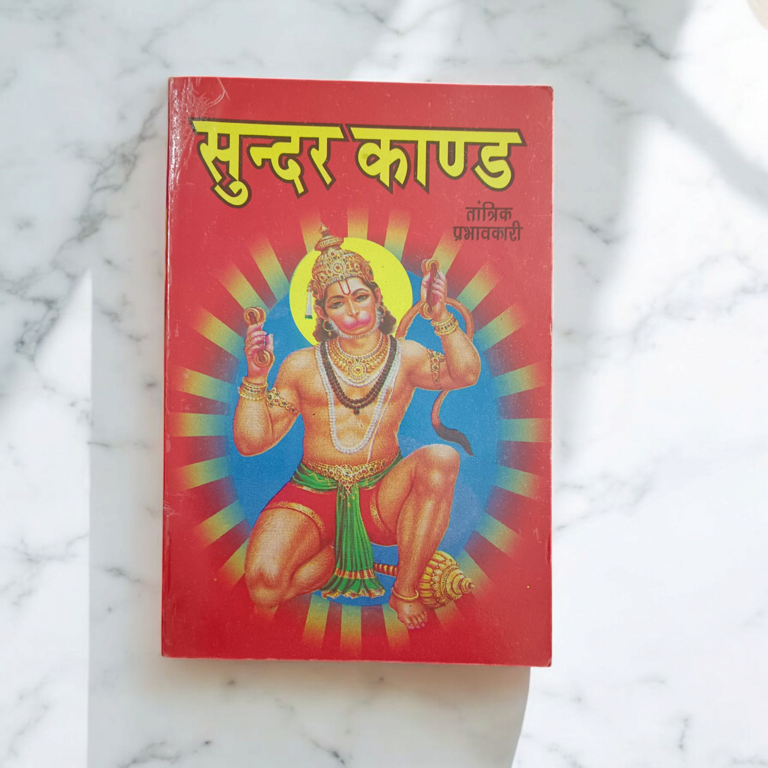A beautifully designed Sunder Kand Book in Hindi, with big red font, open to a page of the devotional prayers and praises of Lord Hanuman Ji.