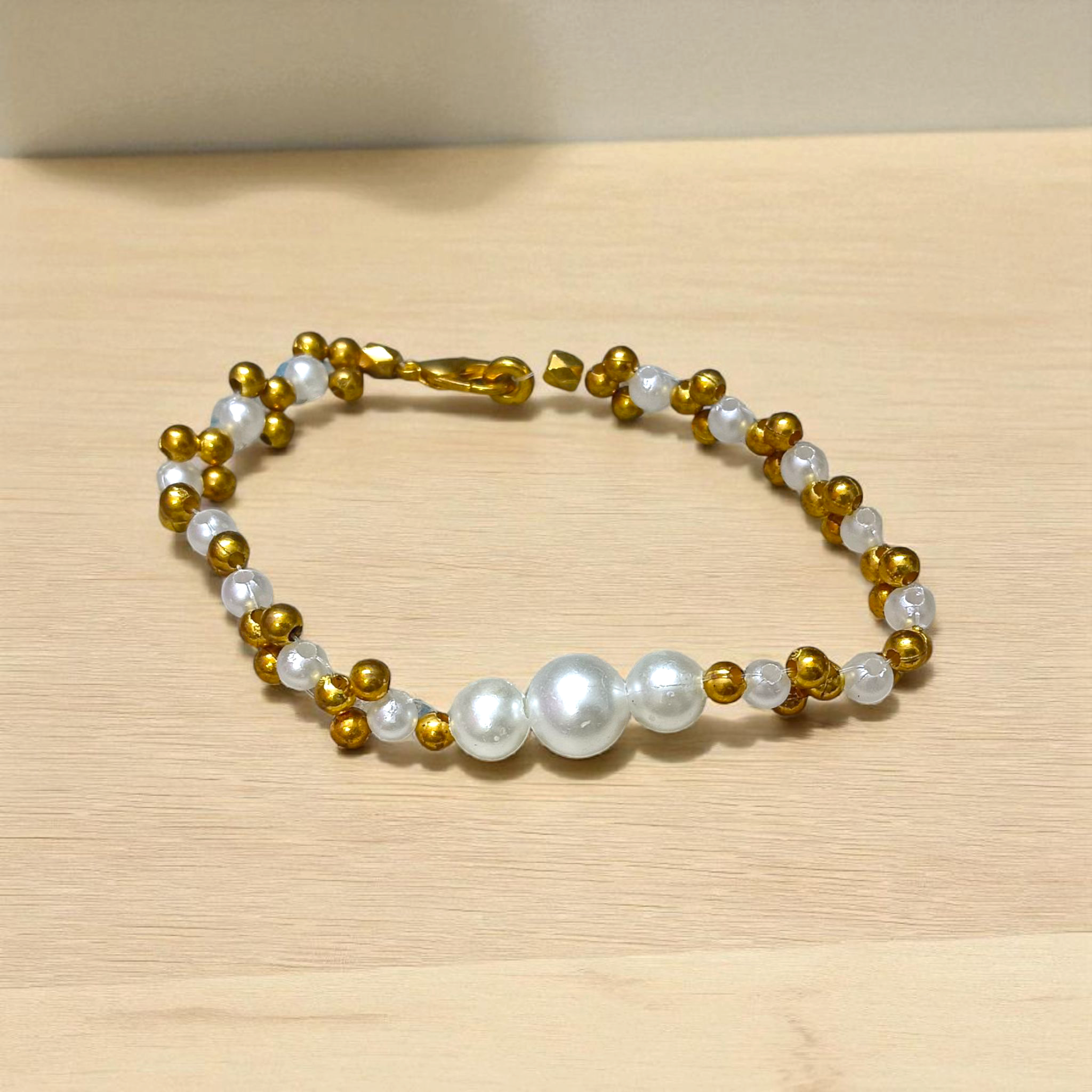 A beautifully handcrafted white and golden pearl designer bracelet, stretchable and elegant—perfect for girls, women, and festive occasions