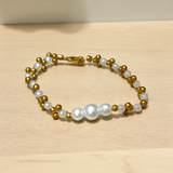 A beautifully handcrafted white and golden pearl designer bracelet, stretchable and elegant—perfect for girls, women, and festive occasions