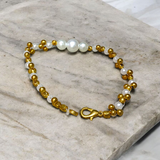 A beautifully handcrafted white and golden pearl designer bracelet, stretchable and elegant—perfect for girls, women, and festive occasions