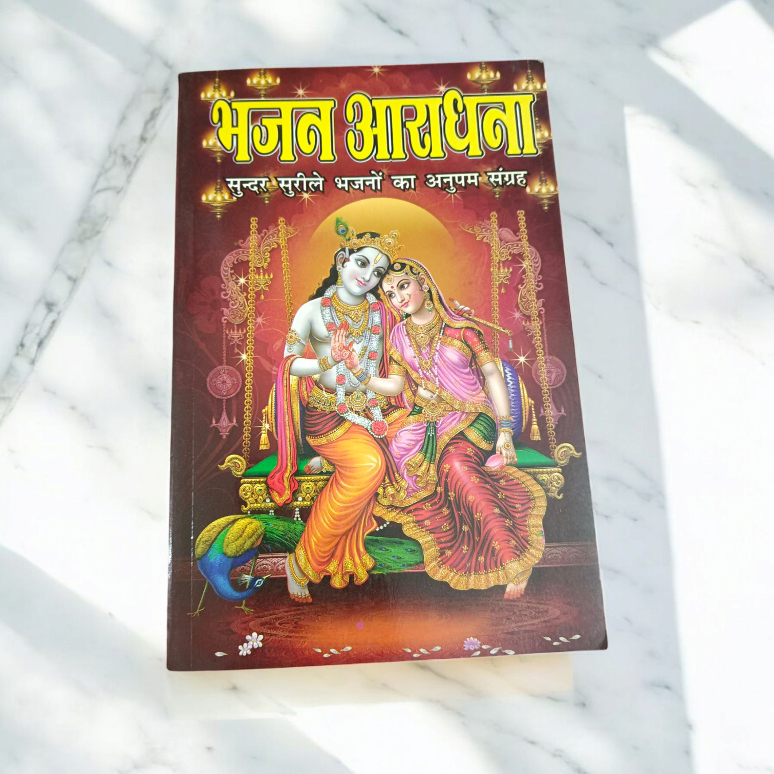 A close-up of a Bhajan Book In Hindi featuring 200+ bhajans and 15+ aartis, with a peaceful spiritual background.