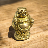 A detailed and polished brass statue of the Laughing Buddha in a standing pose, symbolizing good luck, prosperity, and happiness.