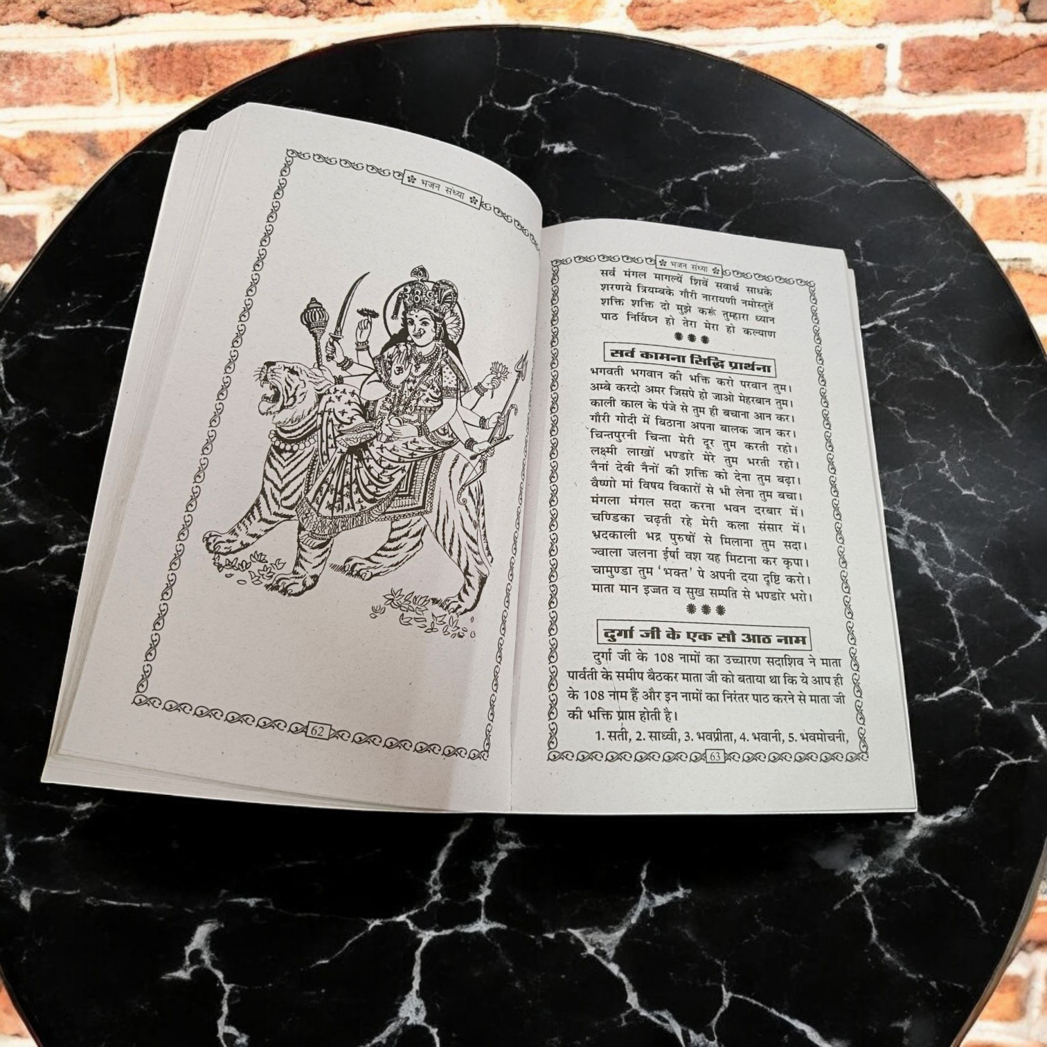 A person holding a Bhajan Book In Hindi featuring devotional bhajans and aartis, with a serene background of a temple.