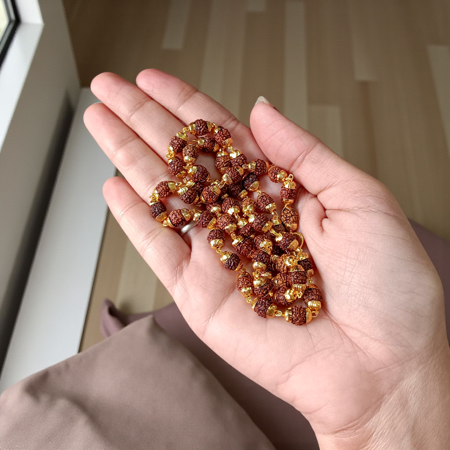 A premium Natural 5 Face Rudraksha Mala with 50 lab-certified 6mm Rudraksha beads, golden caps, and a 1-year golden plating guarantee, symbolizing peace and divine energy