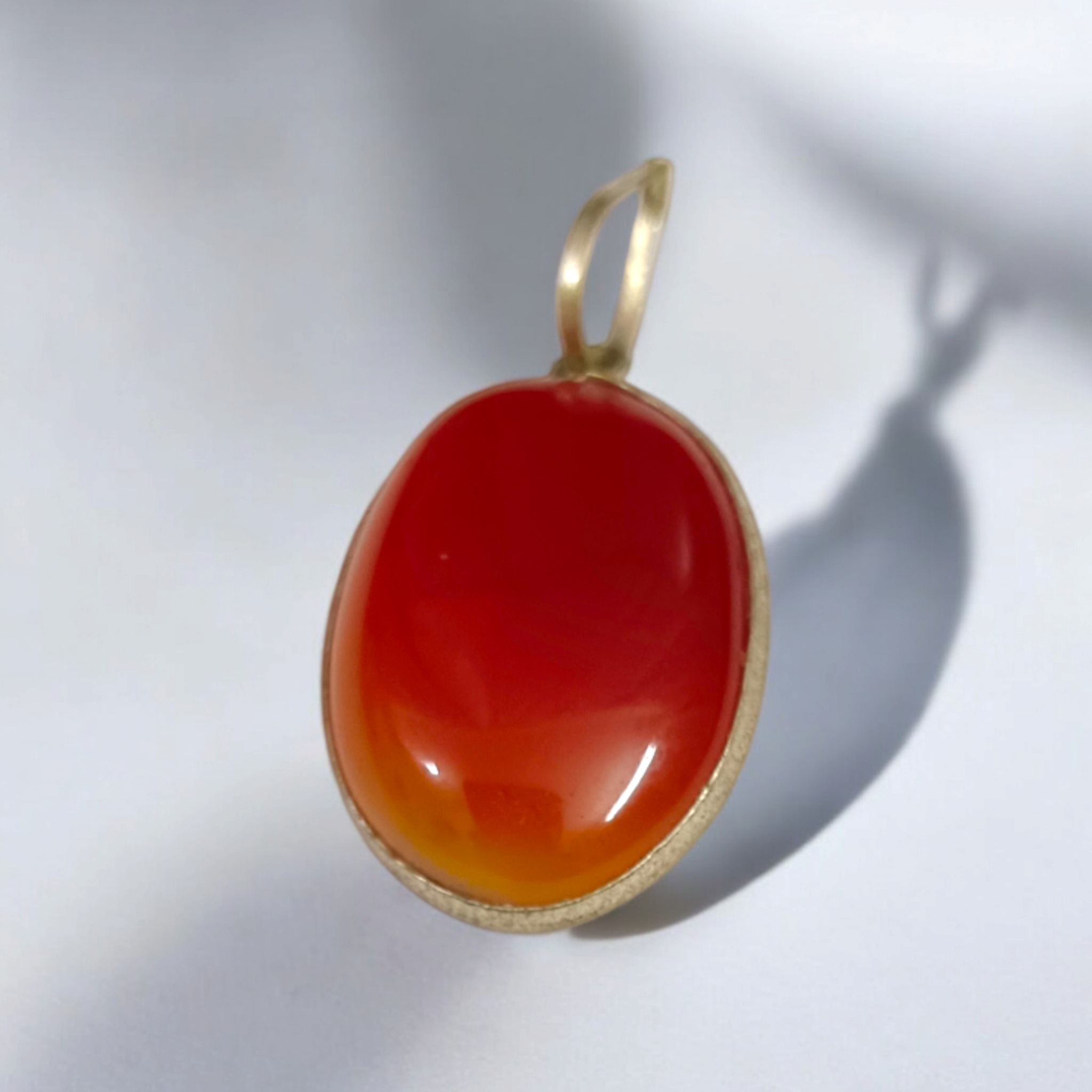 Close-up of the Original Orange Aventurine Pendant on a necklace, showing its vibrant orange hue and smooth, polished surface.