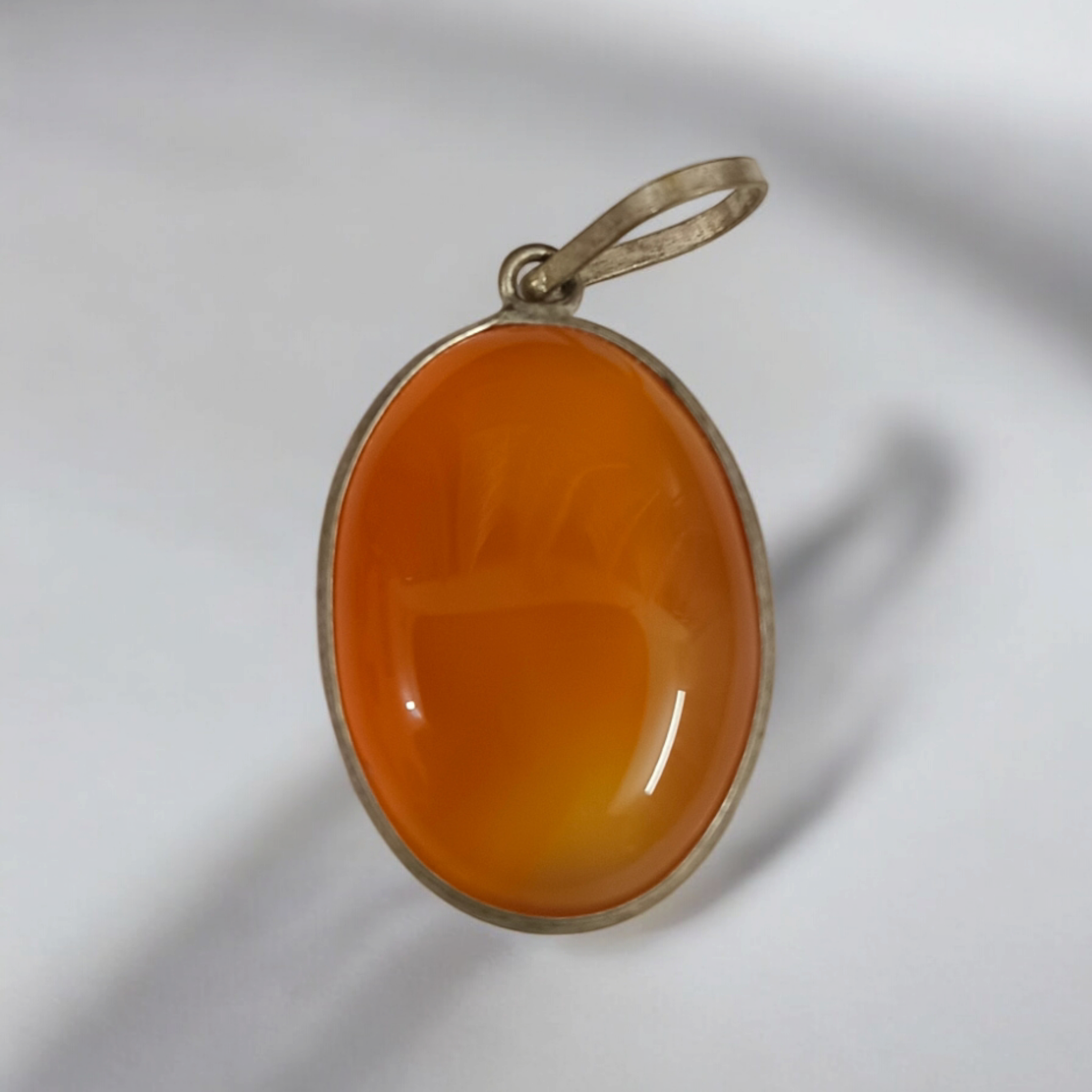 Close-up of the Original Orange Aventurine Pendant on a necklace, showing its vibrant orange hue and smooth, polished surface.