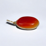 Close-up of the Original Orange Aventurine Pendant on a necklace, showing its vibrant orange hue and smooth, polished surface.