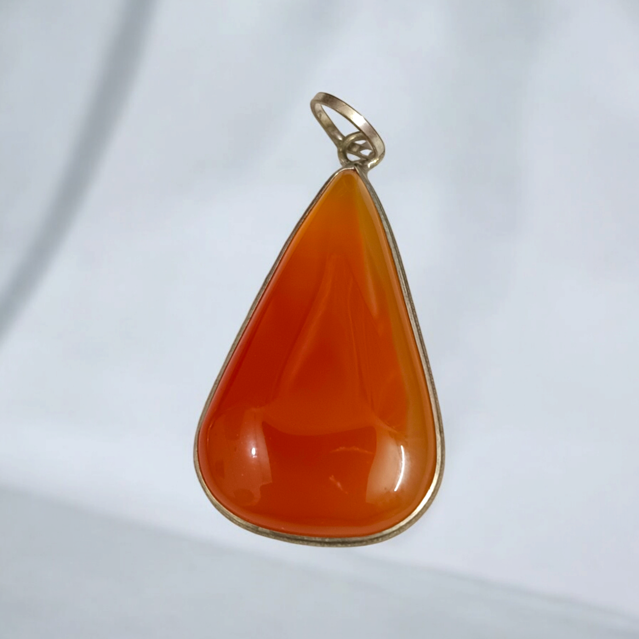 Close-up of the Original Orange Aventurine Pendant on a necklace, showing its vibrant orange hue and smooth, polished surface.
