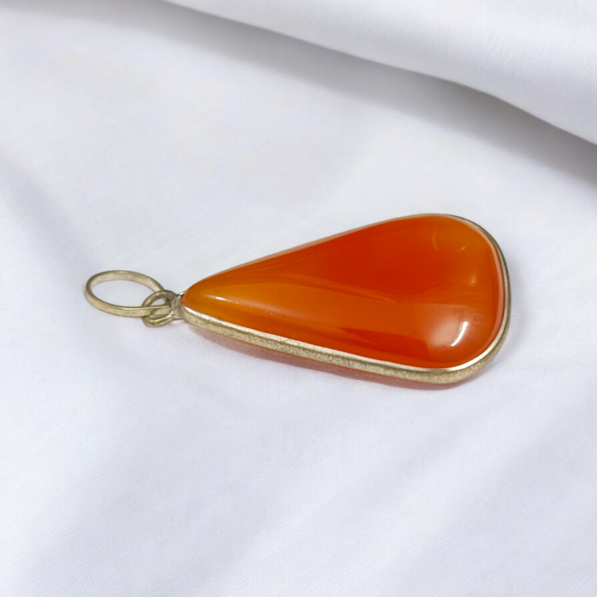 Close-up of the Original Orange Aventurine Pendant on a necklace, showing its vibrant orange hue and smooth, polished surface.