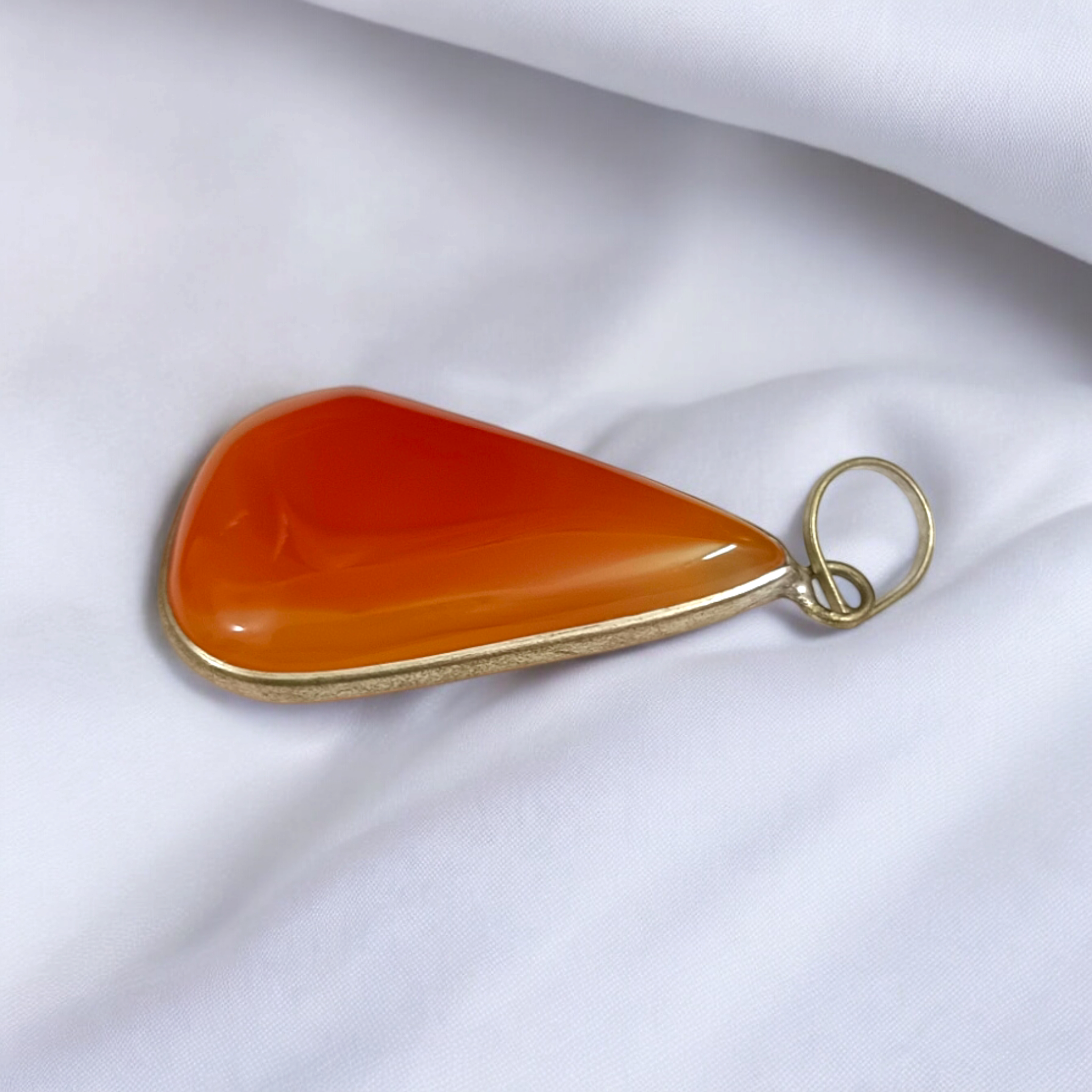 Close-up of the Original Orange Aventurine Pendant on a necklace, showing its vibrant orange hue and smooth, polished surface.