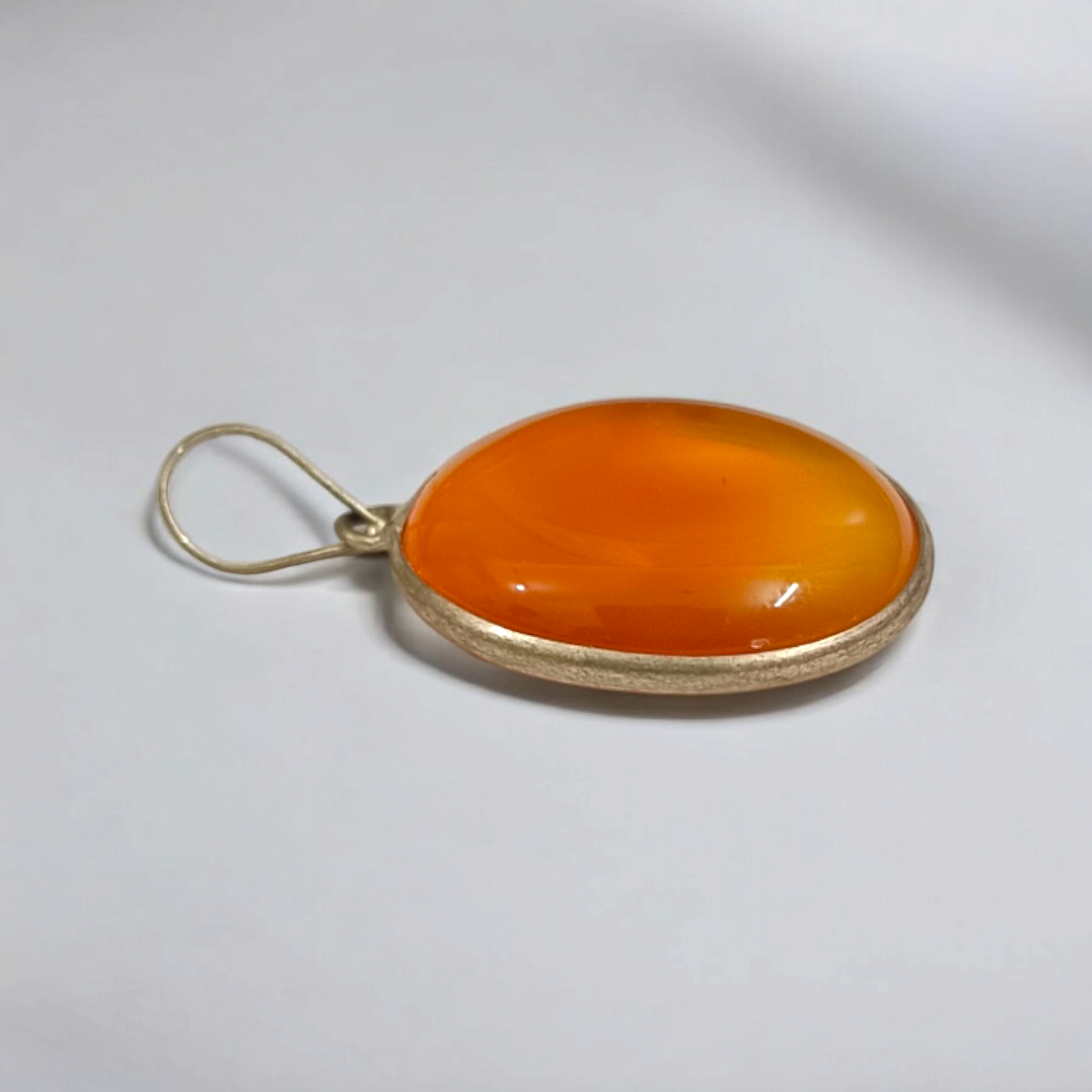 Close-up of the Original Orange Aventurine Pendant on a necklace, showing its vibrant orange hue and smooth, polished surface.