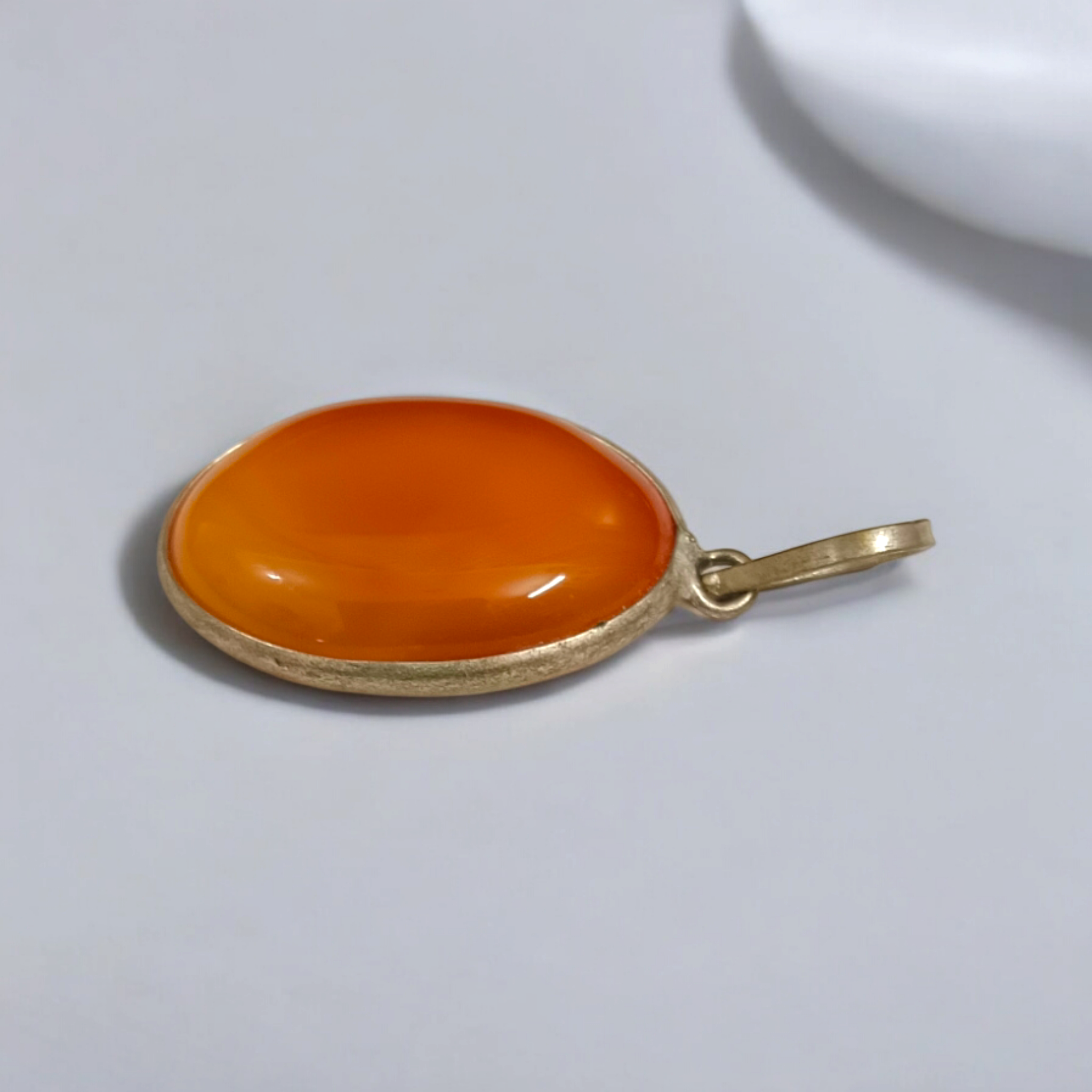 Close-up of the Original Orange Aventurine Pendant on a necklace, showing its vibrant orange hue and smooth, polished surface.