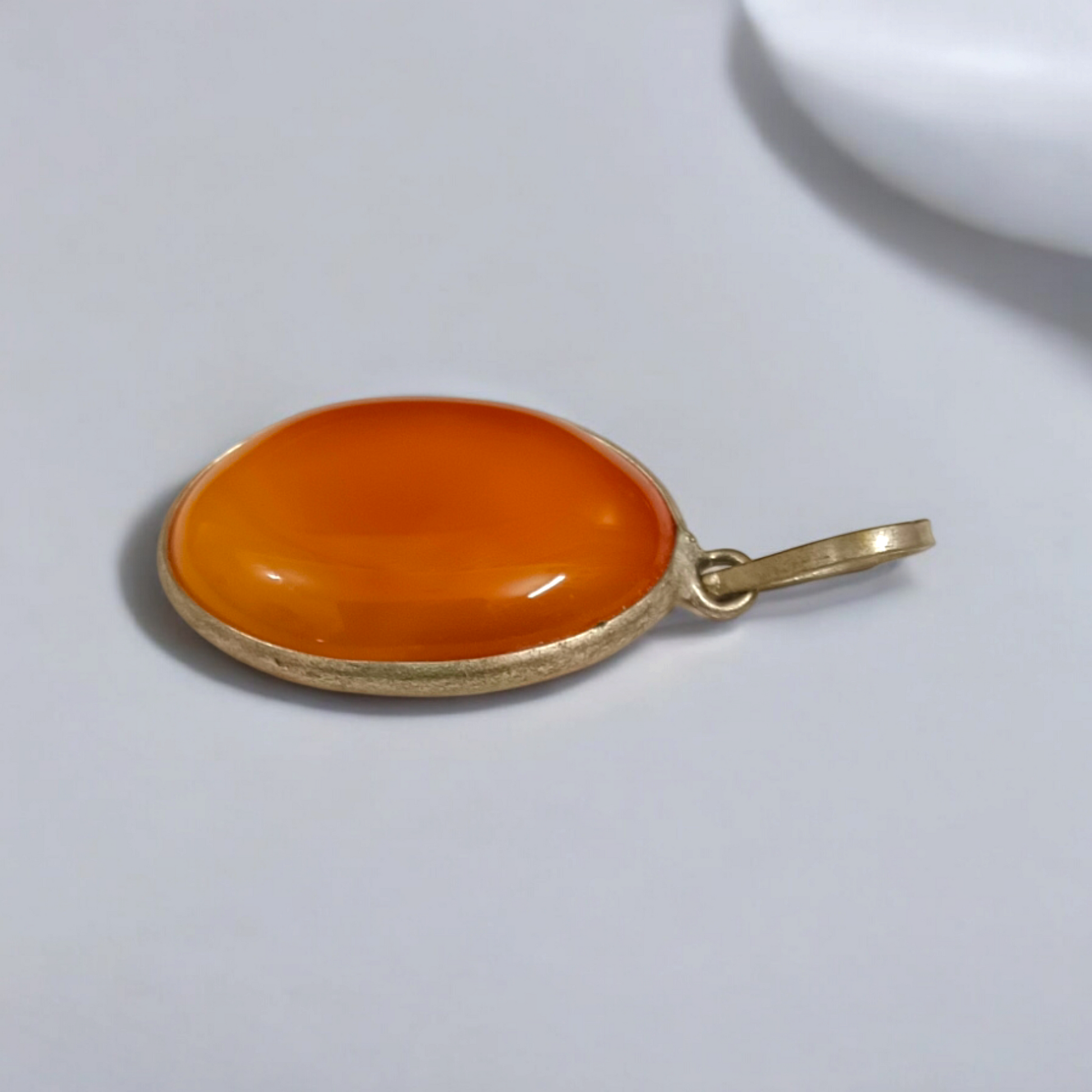 Close-up of the Original Orange Aventurine Pendant on a necklace, showing its vibrant orange hue and smooth, polished surface.