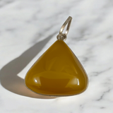 Close-up of the Original Yellow Aventurine Pendant, highlighting its smooth, vibrant yellow hue and polished surface on a necklace.