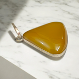 Close-up of the Original Yellow Aventurine Pendant, highlighting its smooth, vibrant yellow hue and polished surface on a necklace.