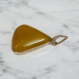 Close-up of the Original Yellow Aventurine Pendant, highlighting its smooth, vibrant yellow hue and polished surface on a necklace.