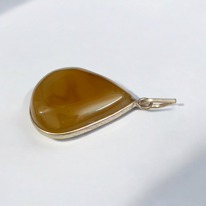Close-up of the Original Yellow Aventurine Pendant, highlighting its smooth, vibrant yellow hue and polished surface on a necklace.