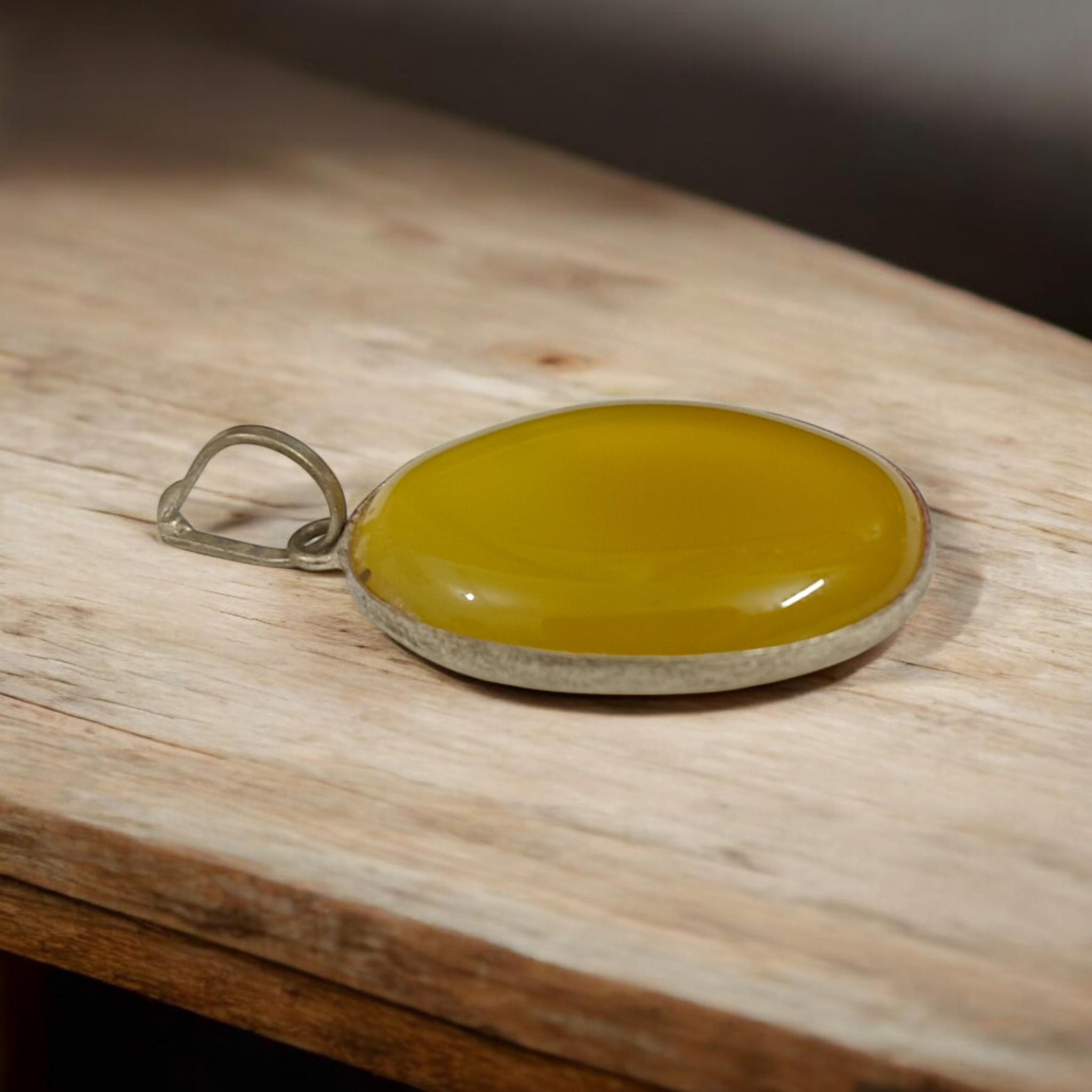 Close-up of the Original Yellow Aventurine Pendant, highlighting its smooth, vibrant yellow hue and polished surface on a necklace.