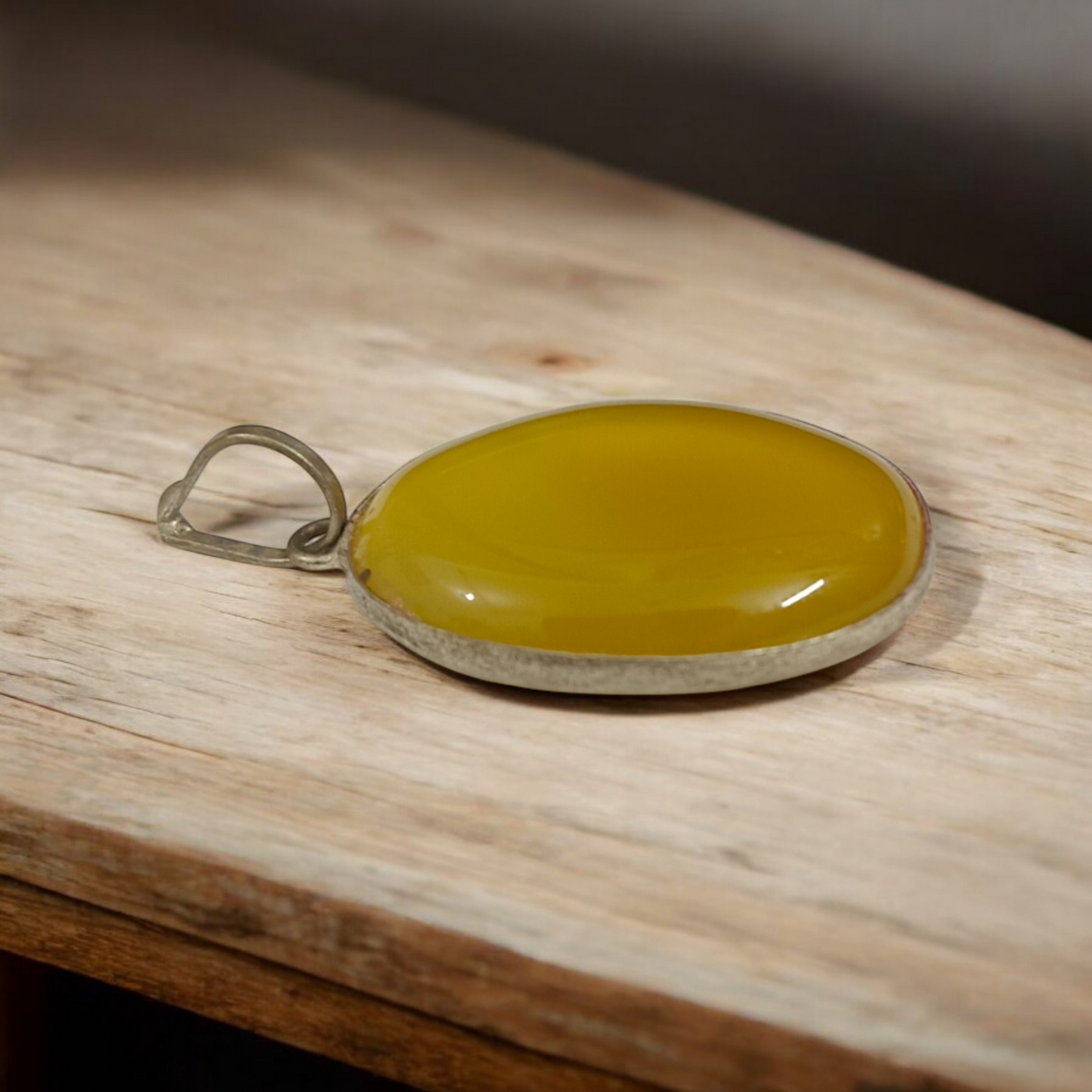 Close-up of the Original Yellow Aventurine Pendant, highlighting its smooth, vibrant yellow hue and polished surface on a necklace.
