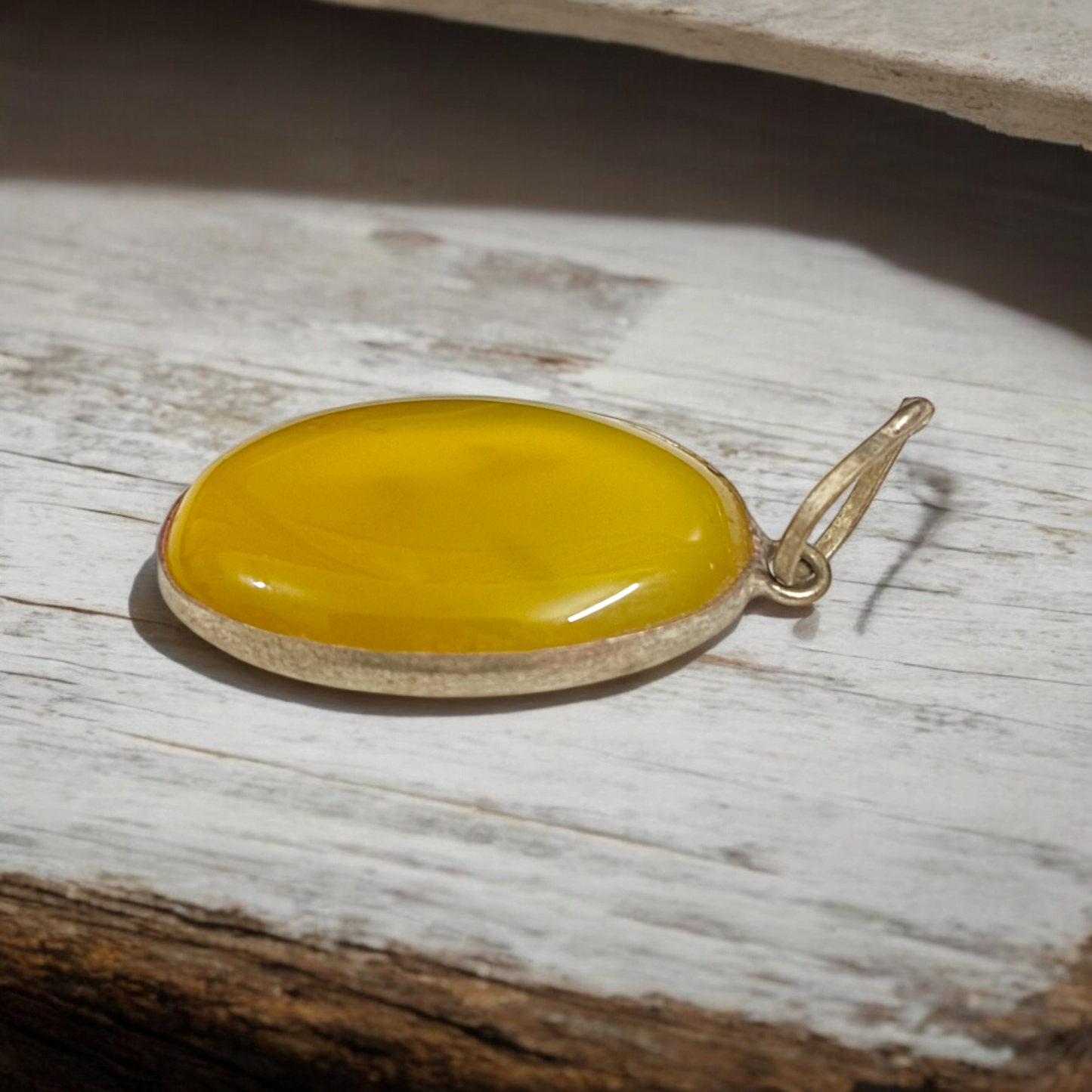 Close-up of the Original Yellow Aventurine Pendant, highlighting its smooth, vibrant yellow hue and polished surface on a necklace.