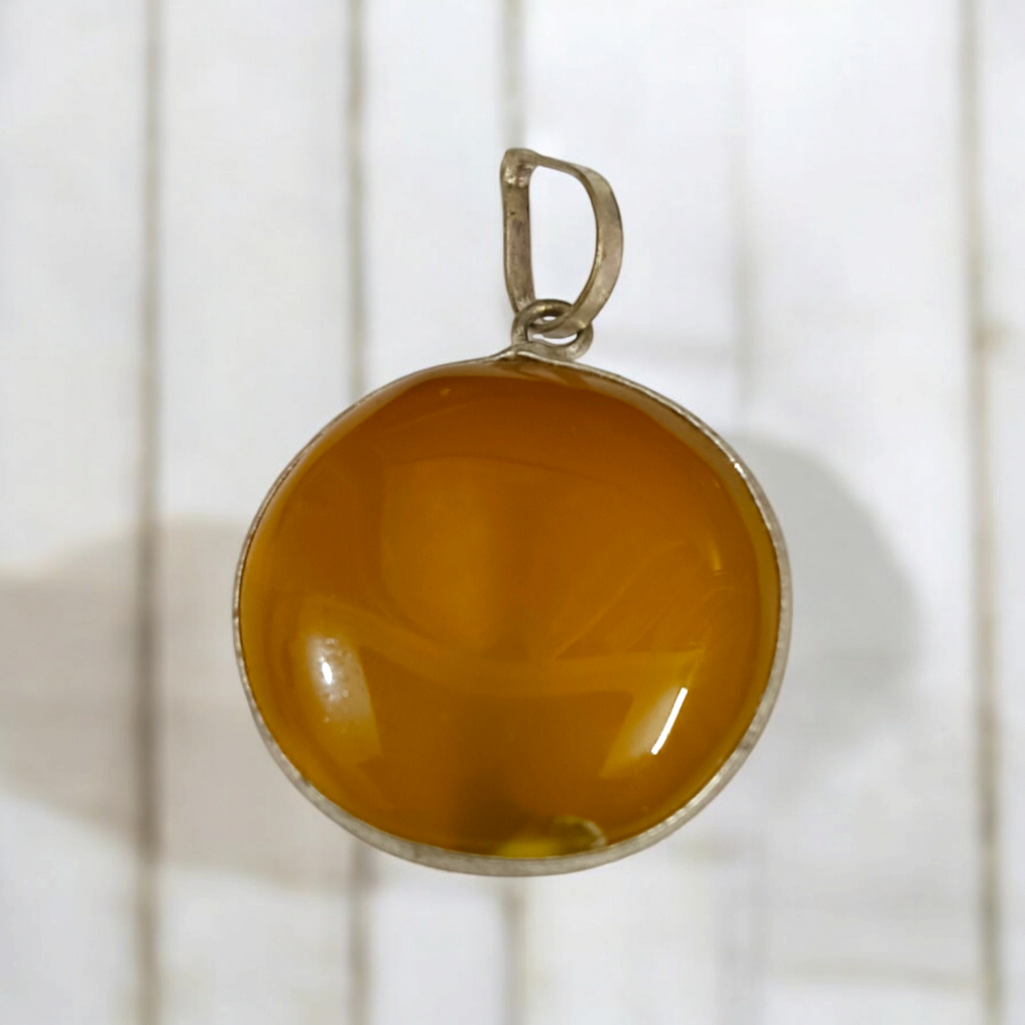 Close-up of the Original Yellow Aventurine Pendant, highlighting its smooth, vibrant yellow hue and polished surface on a necklace.