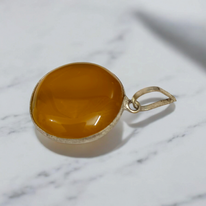 Close-up of the Original Yellow Aventurine Pendant, highlighting its smooth, vibrant yellow hue and polished surface on a necklace.