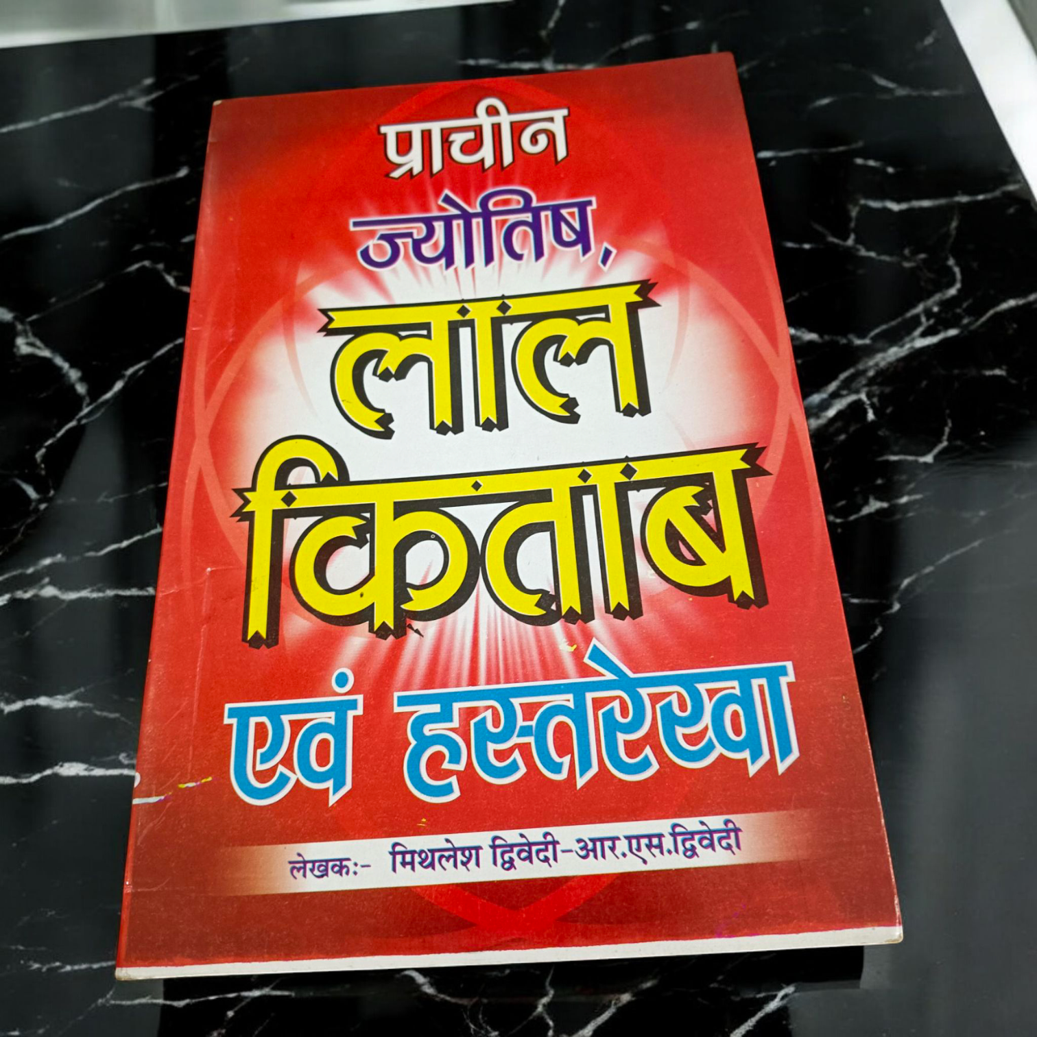 Description of the image: The cover of Lal Kitab Aur Hastrekha Prachin Jyotish | Hindi Book, featuring astrological and palmistry symbols intertwined with ancient mystical designs.
