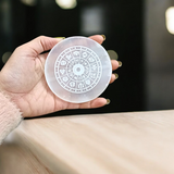 Engraved selenite crystal charging plate with zodiac signs, used for cleansing and recharging crystals, meditation, pooja, and spiritual home décor