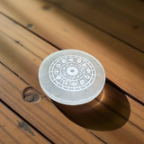 Engraved selenite crystal charging plate with zodiac signs, used for cleansing and recharging crystals, meditation, pooja, and spiritual home décor