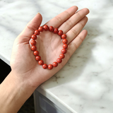 Image of a Natural Red Jasper Bracelet with 8mm polished beads, stretchable cord, and lab-certified gemstone design