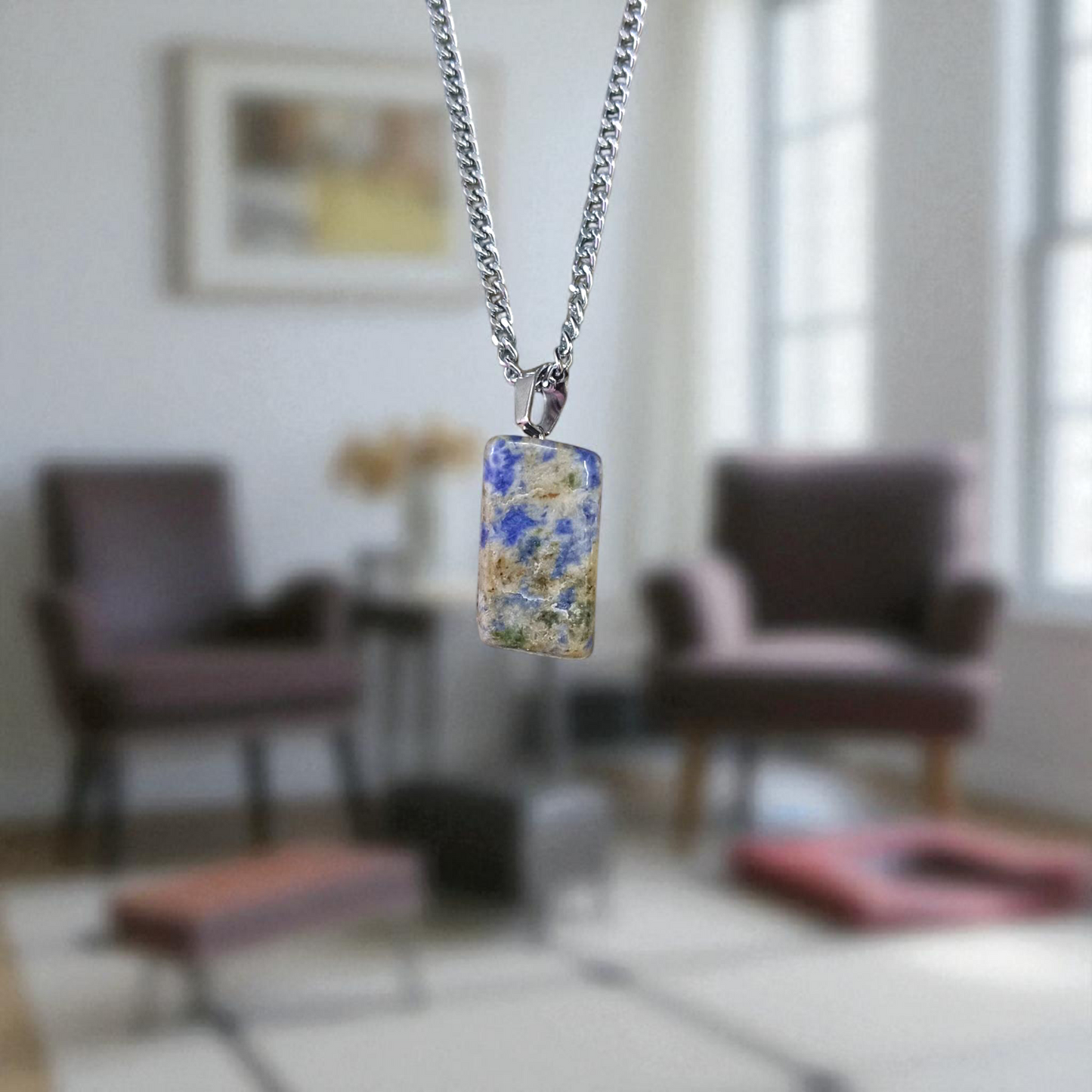 Image of a deep blue Lapis Lazuli Pendant with shimmering golden flecks, attached to a white metal chain – ideal for daily wear and spiritual benefits