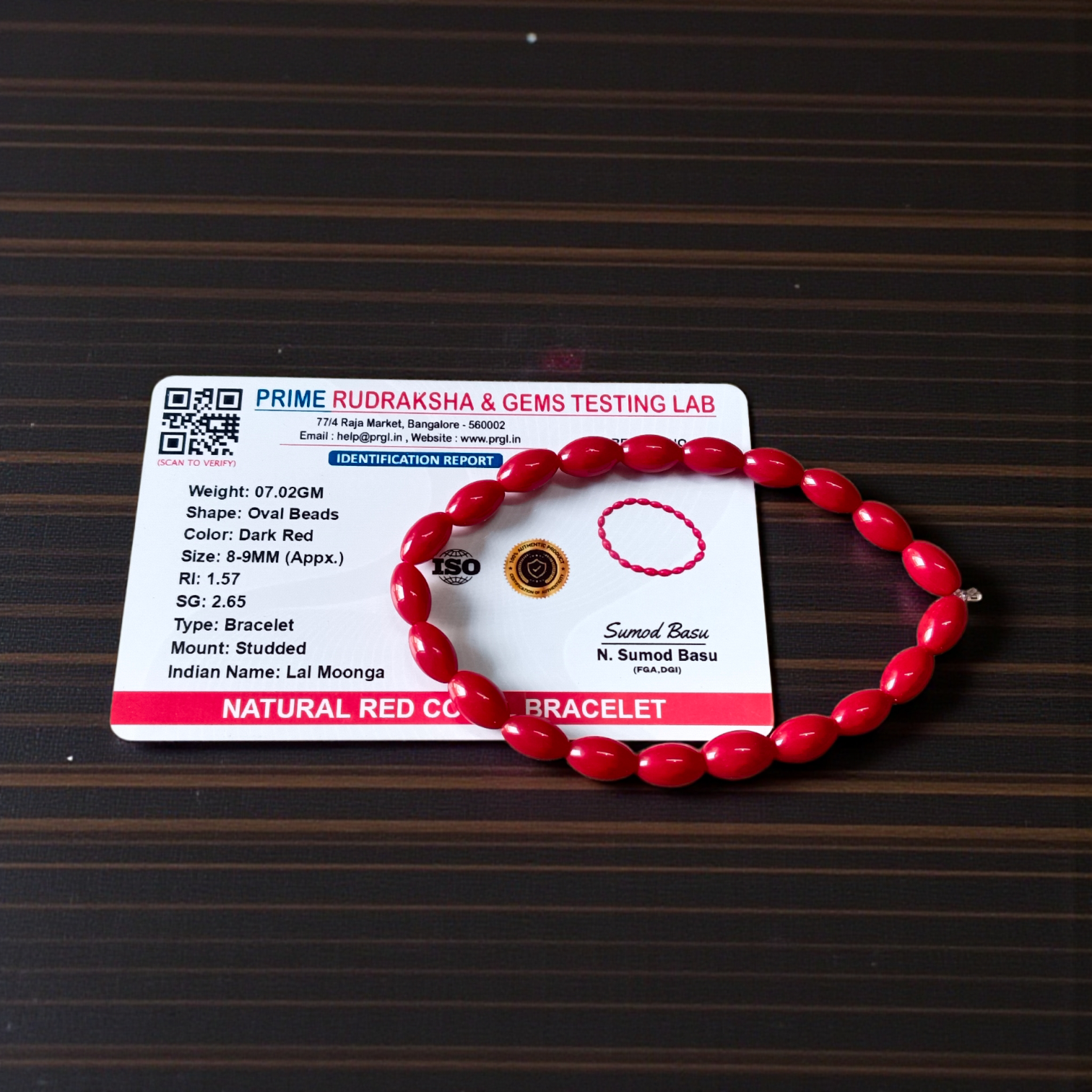 Lab Certified Lal Monga (Red Coral) Bracelet with polished red beads placed on a traditional cloth backdrop