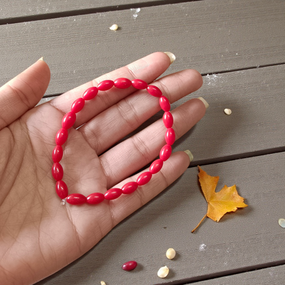 Lab Certified Lal Monga (Red Coral) Bracelet with polished red beads placed on a traditional cloth backdrop