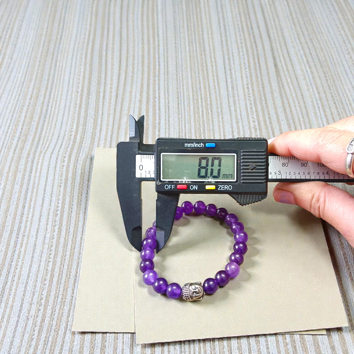 Natural Amethyst Bracelet with polished purple beads, stretchable design, placed on a neutral background 