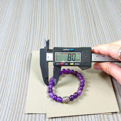 Natural Amethyst Bracelet with polished purple beads, stretchable design, placed on a neutral background 