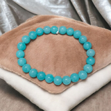 Natural Blue Chalcedony Bracelet made with 8mm smooth round stretchable beads, lab certified, placed on a natural stone background