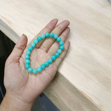 Natural Blue Chalcedony Bracelet made with 8mm smooth round stretchable beads, lab certified, placed on a natural stone background