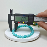 Natural Blue Chalcedony Bracelet made with 8mm smooth round stretchable beads, lab certified, placed on a natural stone background