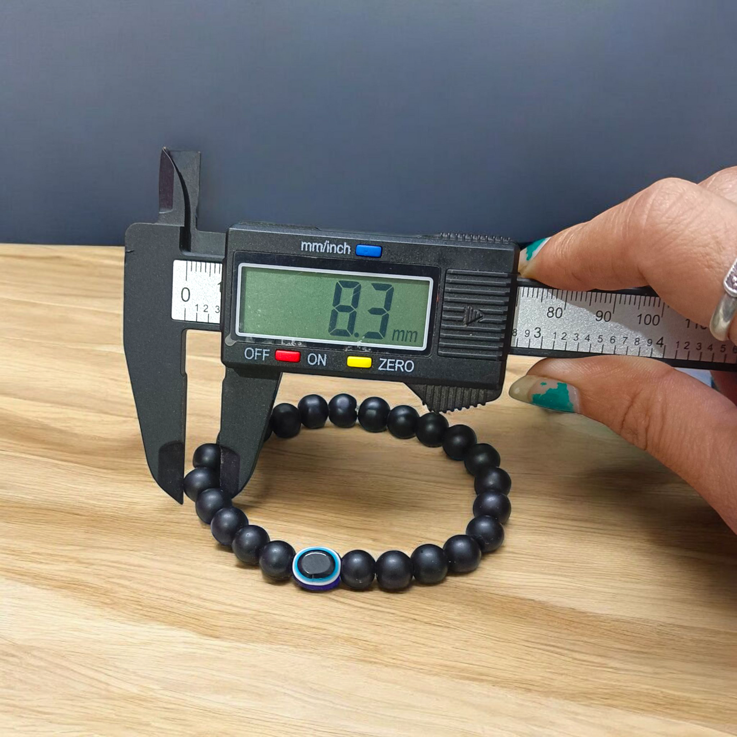 Natural Karungali (Ebony Wood) Bracelet with 8mm round beads and a central Evil Eye bead, stretchable and lab certified, displayed on a neutral background