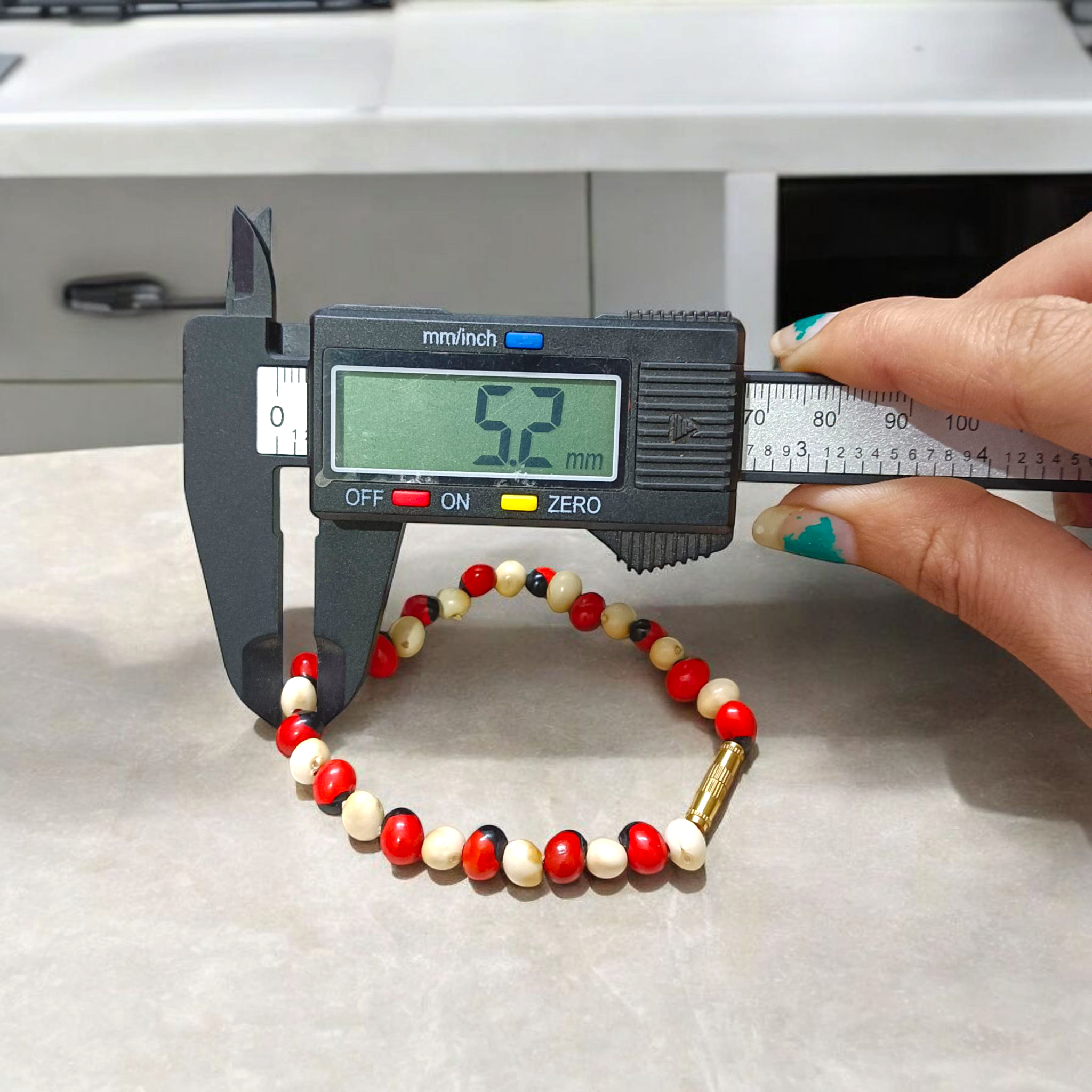 Natural Red and White Gunja bracelet with 5mm lab certified beads on stretchable cord, displayed on a neutral background