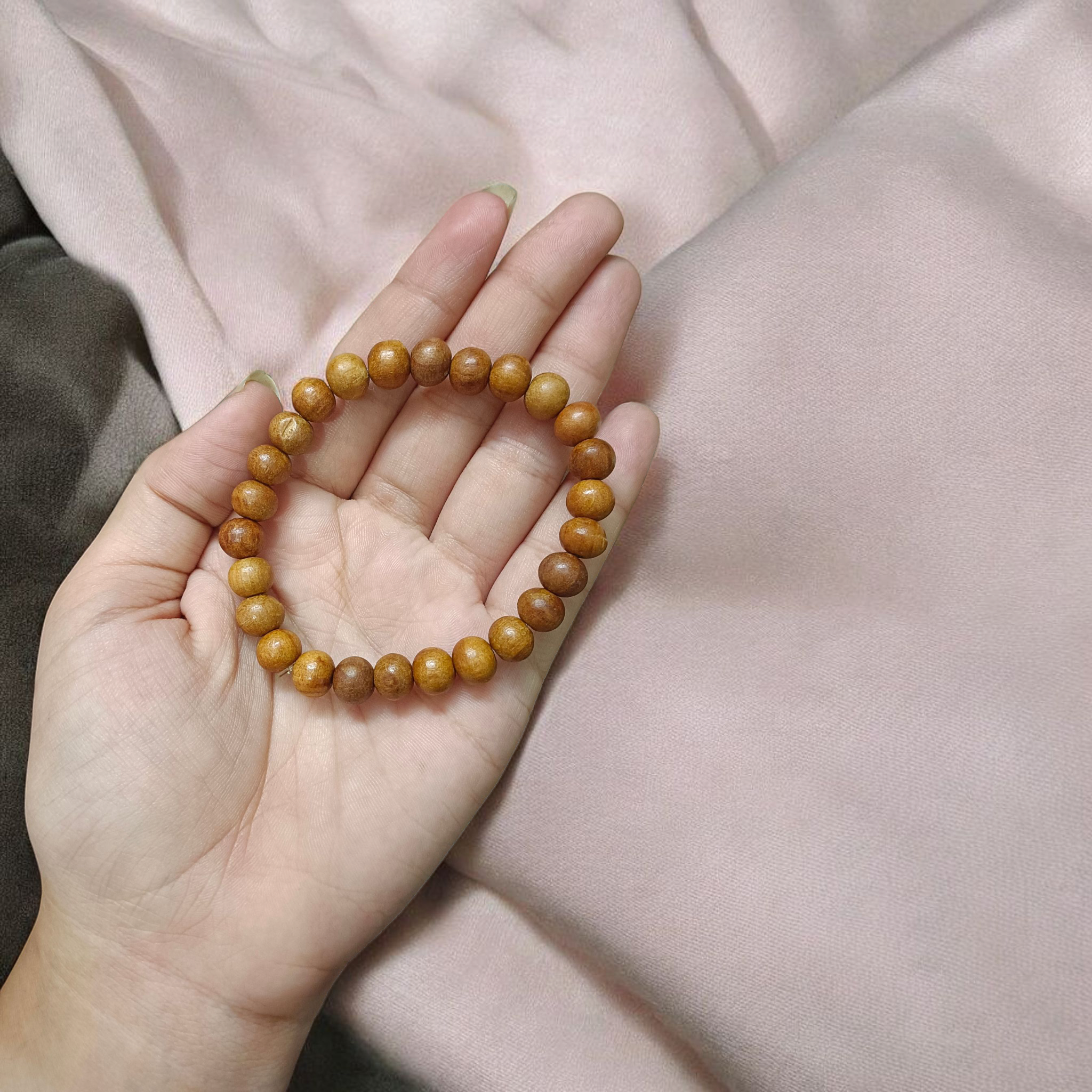 Natural White Sandalwood Bracelet with 8mm round stretchable beads, lab certified, displayed on a wooden surface