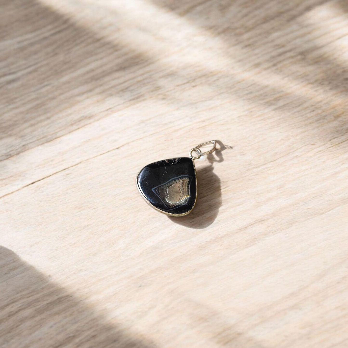 Natural lab certified Sulemani Hakik pendant with black and grey bands, fitted in a wearable setting for healing and protection