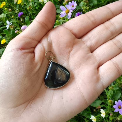 Natural lab certified Sulemani Hakik pendant with black and grey bands, fitted in a wearable setting for healing and protection