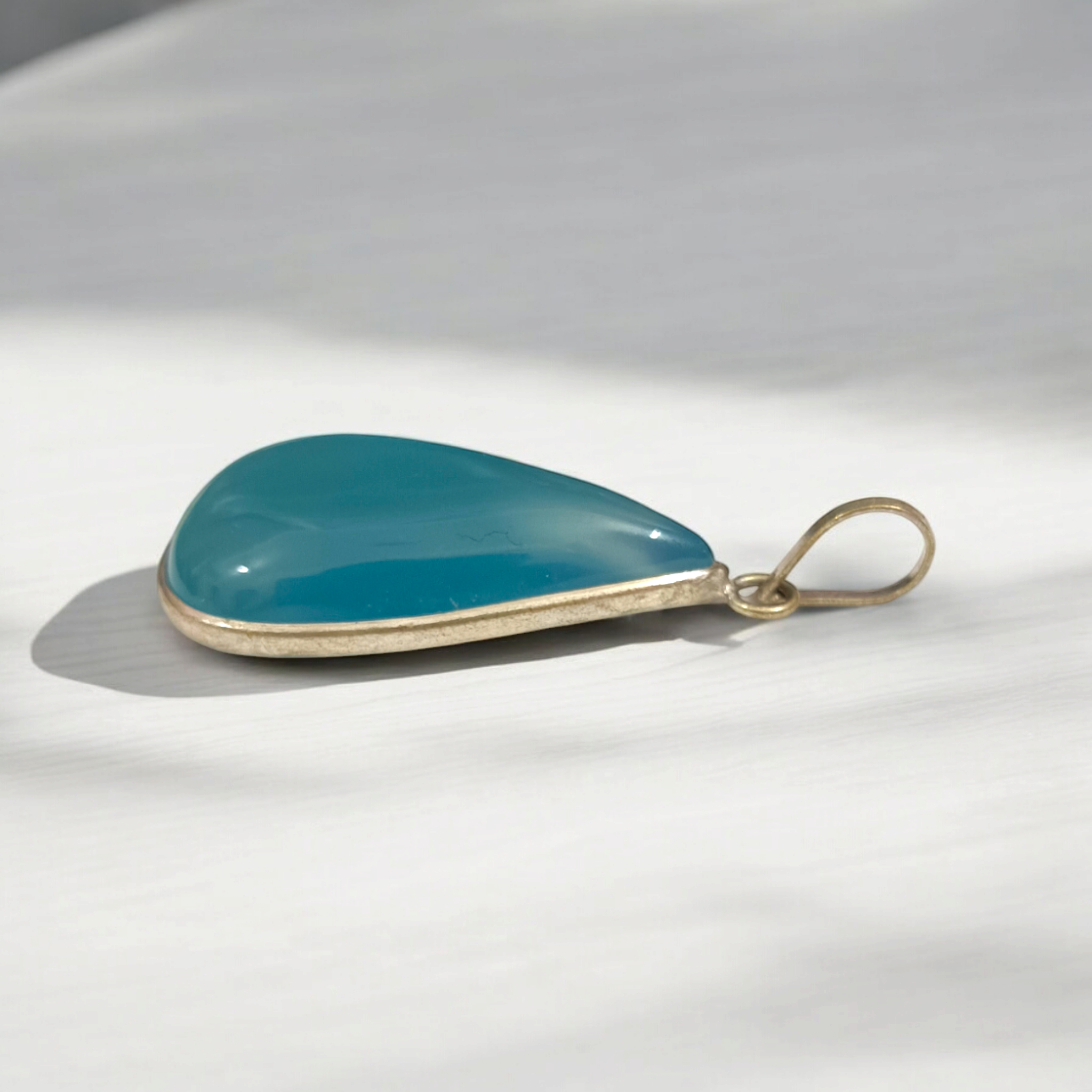 Original Firoza pendant with a vibrant turquoise hue, displayed on a necklace, highlighting its polished finish and elegant design.